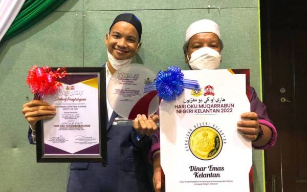 Asif (kiri) dan bapanya, Suhaimi menunjukkan anugerah yang diperolehi selebriti itu pada Majlis Sambutan Hari Orang Kurang Upaya (OKU) Muqarrabun Peringkat Negeri Kelantan 2022 di Pusat Tarbiah Islamiah Pengkalan Chepa, di Kota Bharu pada Khamis.