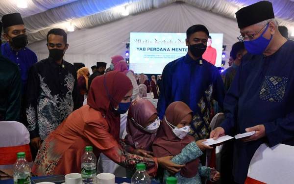 Ismail Sabri (kanan) menyampaikan sumbangan duit raya kepada anak angkatnya Nur Qurratu Ain Nabilah Benyajeed dan kakaknya Nur Rawdhah Nabilah Benyajeed pada Majlis Berbuka Puasa Bersama Kepimpinan Sayap Pemuda dan Puteri UMNO Bahagian seluruh negara di kediaman rasminya Seri Perdana malam ini. - Foto Bernama