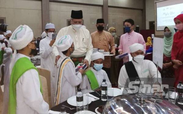 Annuar menyampaikan sumbangan sambil beramah mesra dengan pelajar tahfiz pada majlis iftar di Alor Setar.