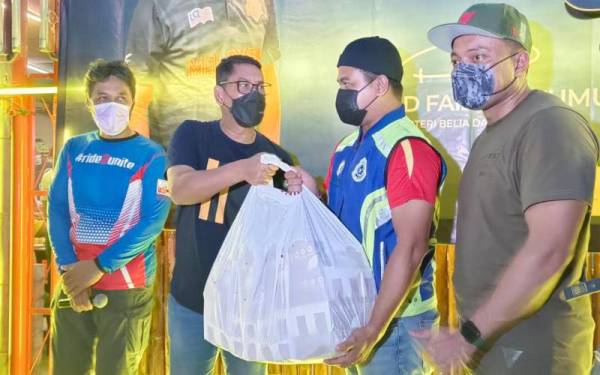 Ahmad Faizal (dua dari kiri) menyerahkan makanan sahur kepada wakil balai polis pada program Kembara Sahur bersama Funride Riders di Tambun pada Sabtu.