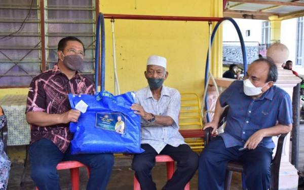 Abdul Rahman (kiri) menyampaikan bakul makanan kepada salah seorang peneroka ketika program Tradisi Ziarah Kasih di Parlimen Lipis.