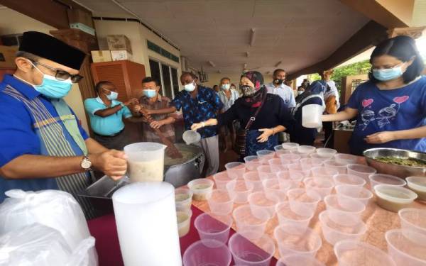 Penduduk berbilang kaum Taman Rasa Sayang bergotong-royong memasak bubur lambuk.