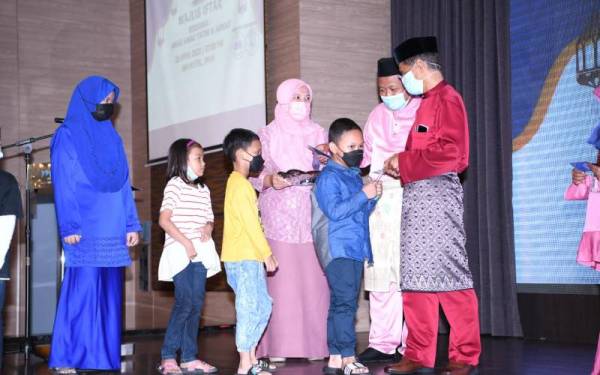 Zahar (kanan) menyampaikan duit raya kepada anak-anak yatim dan asnaf yang diraikan DPMP dalam Majlis Iftar di sebuah hotel di Ipoh.