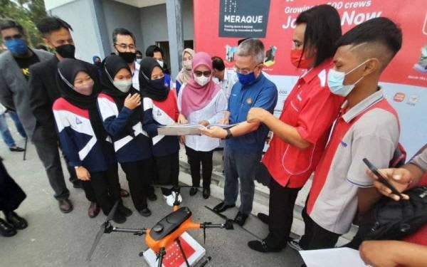 Dr Adham (tengah) dan Norlizah dalam Program CSR Sekolah Angkat 'Fly With Meraque' di Dewan Majlis Daerah Kota Tinggi (MDKT) Pejabat Cawangan Bandar Tenggara, Kota Tinggi, pada Ahad.