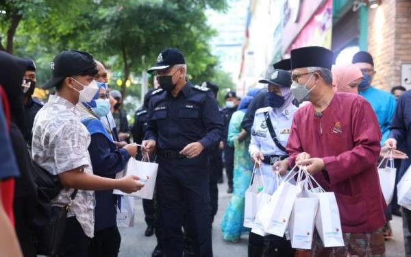 Acryl (tiga dari kanan) dan Idham (kanan) mengedarkan pek makanan kepada orang ramai di Jalan Esfahan, Kuala Lumpur.