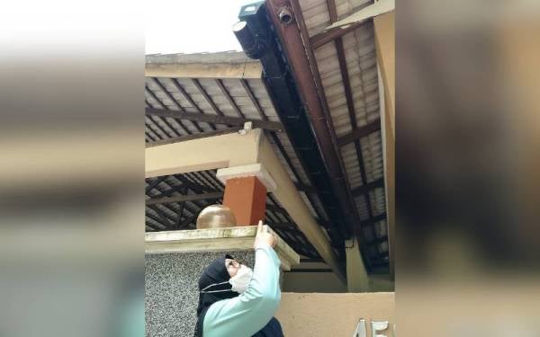 Fadzilah menunjukkan palung yang dipenuhi daun kering menyebabkan laluan air tersumbat sehingga mengalir ke siling dan dinding rumah terutama ketika hujan lebat.