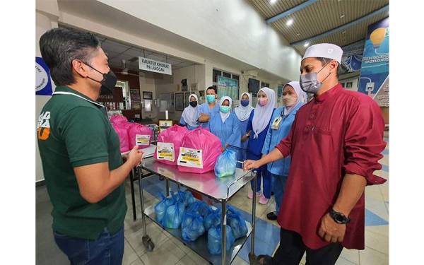 Khaliq Mehtab (kiri) menyantuni kakitangan Hospital Kepala Batas selepas menyerahkan pek makanan yang dibawa peserta konvoi Program Perda4U: Singgah Sahur 2022.