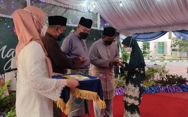 Menteri Besar Kedah, Datuk Seri Muhammad Sanusi Md Nor (dua,kanan) menyerahkan sumbangan kepada penerima sambil diiringi Wan Hassan (tengah) pada Majlis Berbuka Puasa Menteri Besar Kedah bersama warga PDRM di Dataran Kawad IPK Kedah, Alor Setar pada Rabu.