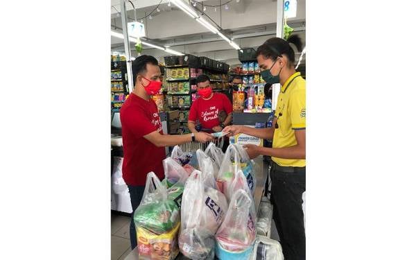 Norhakimi (tengah) dan Mohamad Noordin membeli barangan keperluan untuk disumbangkan kepada penerima.