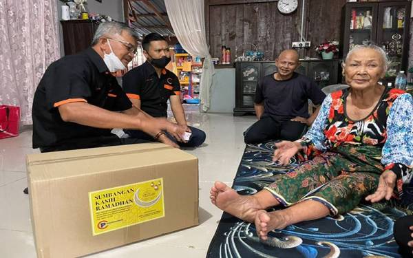 Zainuddin (kiri) turut menyampaikan sumbangan kepada 51 keluarga asnaf, fakir dan miskin sempena Program Sumbangan Kasih Ramadan.