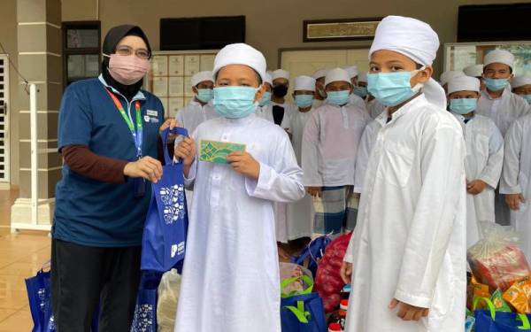 Sriyusni menyampaikan sumbangan kepada salah seorang pelajar.