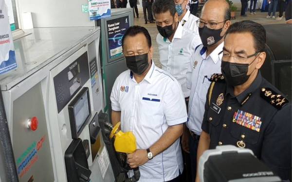 Alexander (kiri) menunjukkan pam petrol bersubdisi RON95 sewaktu mengadakan lawatan ke sebuah stesen minyak di Jalan Lingkaran Dalam, Johor Bahru pada Khamis.