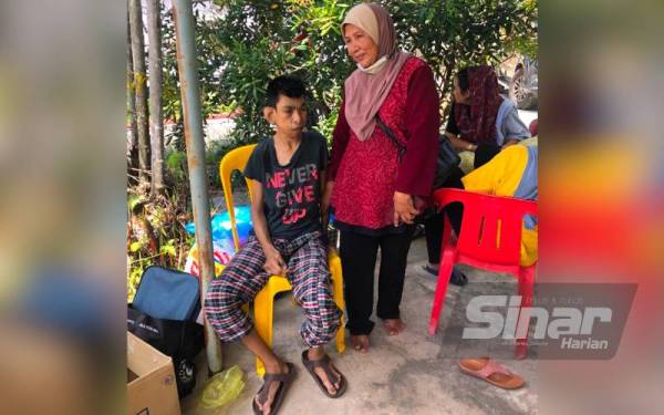 Mangsa kebakaran, Che Nab Che Jaafar,65, (kanan) bersama seorang anak orang kurang upaya (OKU), Nor Haslinda Othman, 42, berteduh sementara di rumah jiran di lokasi kejadian.