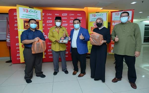 Zura (dua dari kanan) dan Fakaruddin (tengah) menyerahkan simbolik pek makanan kepada Pengurus Kanan Tugas-Tugas Khas Kumpulan Karangkraf, Hashim Anang (dua dari kiri).