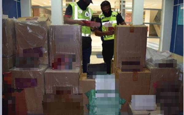 Anggota Briged Tenggara PGA memeriksa rokok yang dirampas dianggarkan bernilai RM344,436.20 dalam satu serbuan di sebuah rumah di Indera Mahkota pada Khamis. - Foto PGA