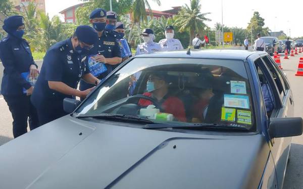 Agus Salim (kiri) beramah mesra dengan pengguna jalan raya semasa Majlis Pelancaran Op Selamat 18 sempena Hari Raya Aidilfitri IPD Sabak Bernam di Kilometer 71 Jalan Teluk Intan-Klang pada Jumaat.
