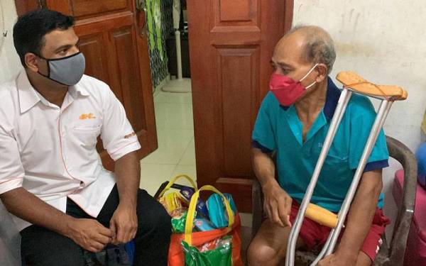 Abdul Rashid (kiri) ketika melawat dan menyampaikan bantuan kepada Othman di rumahnya di Taman Johor Jaya, Johor Bahru, pada Sabtu.