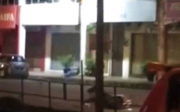 Tangkap layar video tular menunjukkan seorang penunggang motosikal terjatuh akibat terbabas ketika lari daripada pemeriksaan polis.