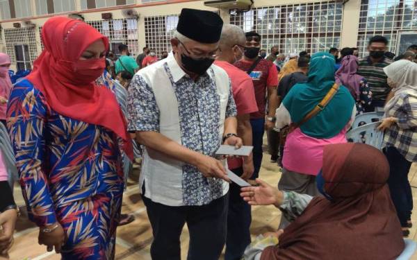 Noh (dua, kanan) menyampaikan sumbangan Aidilfitri kepada salah seorang penerima di Dewan Dato' Hormat Tanjong Karang, pada Ahad.