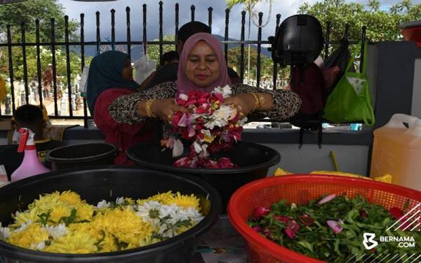 Rosinah menunjukkan pelbagai jenis bunga yang dijual di Tanah Perkuburan Islam Jalan Perak. - Bernama