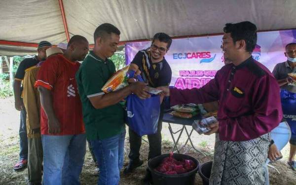 Muhamad Rosni (kanan) menyampaikan sumbangan Aidilfitri kepada 100 penerima terpilih di Mukim Pedu, Padang Terap.