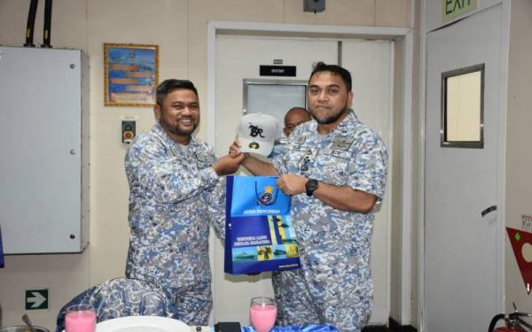 Mohd Reza (kanan) menyerahkan sumbangan kepada salah seorang pegawai TLDM yang bertugas di Pangkalan Laut Tun Sharifah Rodziah.