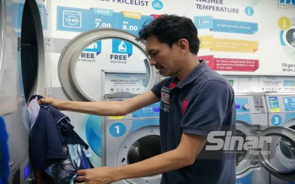 Mohd Fauzi mengeluarkan baju yang siap dikeringkan.