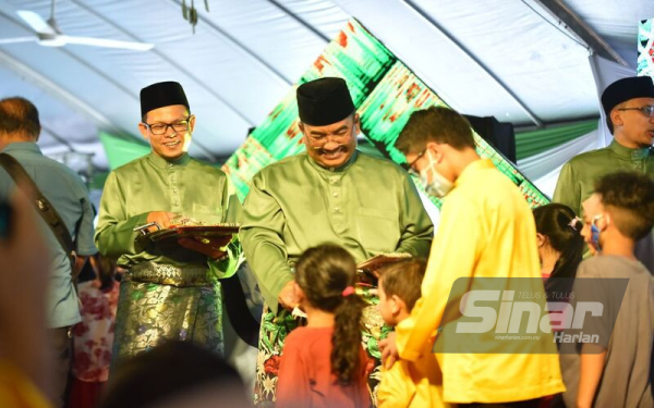 Muhammad Sanusi mengagihkan sampul duit raya kepada kanak-kanak yang hadir memeriahkan Rumah Terbuka Hari Raya Aidilfitri Menteri Besar Kedah di Seri Mentaloon.