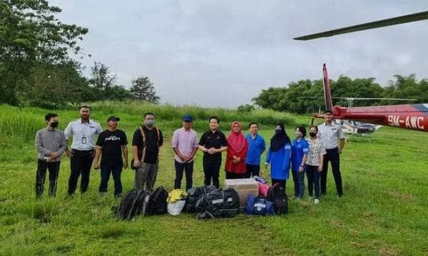 Arthur (enam dari kiri) menghantar guru-guru yang bertugas di Nabawan dengan menaiki helikopter yang disewa khas untuk kembali ke kawasan bagi memulakan sesi persekolahan pada Isnin.