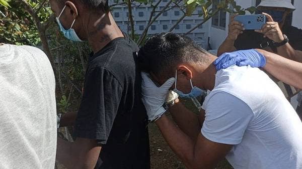 Tertuduh (kanan) dibawa keluar dari Mahkamah Majistret Pontian selepas didakwa pada Isnin.