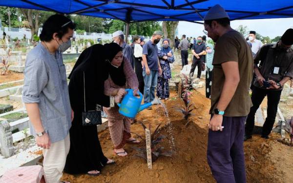 Anak sulung Allahyarham, Nur Nadzmi Nasirah Mohamad Nasir (tiga, kiri) bersama ahli keluarga yang lain menyirami pusara bapanya, Mohamad Nasir Yusoff selepas selamat dikebumikan di Tanah Perkuburan Islam Sungai Kantan, pada Isnin. - Foto Bernama