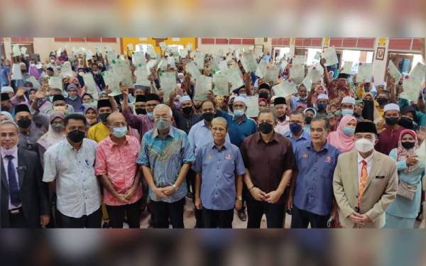 Mahdzir (depan, empat dari kiri) bergambar bersama 160 penerima geran hak milik rumah PPRT Keda selepas Majlis Penyerahan Hak Milik Penempatan Desa Keda di SMK Pokok Sena, Pokok Sena pada Selasa.
