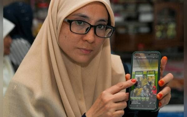 Ibu saudara Iqbal Hasnun Halimi, Siti Norassikin Paralan menunjukkan gambar Iqbal (berbaju melayu maroon) bersama ahli keluarga ketika sambutan Aidilfitri terbaharu, ketika ditemui di Taman Impian Jaya Senai hari ini.- Foto Bernama