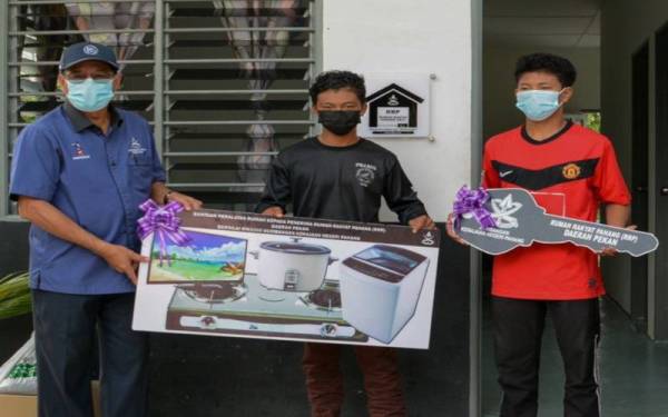 Muhammad Hairil Syafiq (tengah) turut menerima barangan elektrik daripada Khairuddin (kiri) selepas menerima kunci rumah.