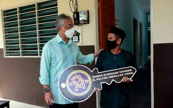 RAUB, 13 Mei -- Yang di-Pertuan Agong Al-Sultan Abdullah Ri'ayatuddin Al-Mustafa Billah Shah (kiri) menyantuni Abdul Aziz Mat Sohor, 62, selepas berkenan mengurniakan kunci rumah serta meninjau rumahnya yang siap dibina di Sungai Sia, Mukim Batu Talam pada Jumaat. - Foto Bernama