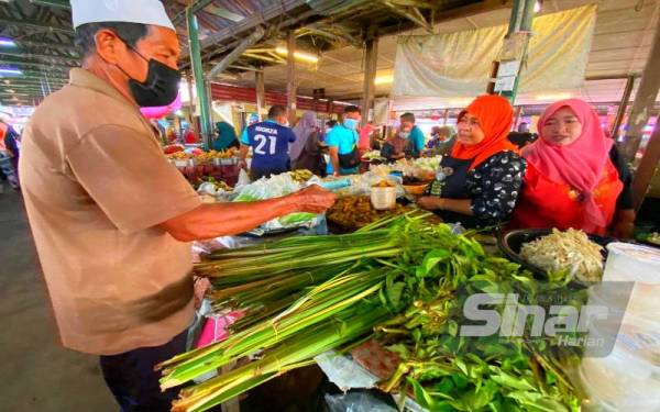 Che Jah (dua dari kanan) melayan pelanggan yang ingin mendapatkan daun palas di gerainya.