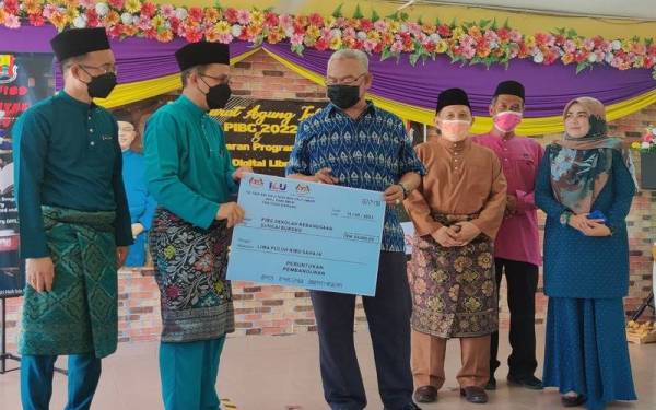 Noh (tiga dari kiri) menyampaikan peruntukan RM50,000 kepada SK Sungai Burong ketika Mesyuarat Agung Tahunan PIBG dan Pelancaran Program Unified Digital Library di Dewan SK Sungai Burung pada Sabtu.