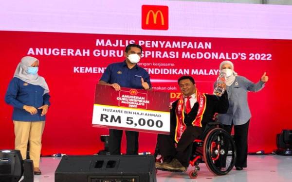 Dr Mohd Radzi (dua dari kiri) menyampaikan Anugerah Guru Inspirasi McDonald’s 2022 kepada seorang guru orang kurang upaya (OKU), Huzaire Ahmad (dua dari kanan).