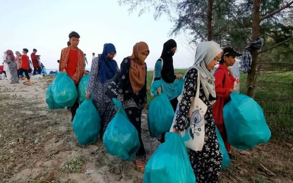 Sukarelawan mengutip sampah dengan memakai baju kurung dan kebaya ketika Program Pembersihan Pantai di Pantai Batu Buruk di Kuala Terengganu pada Jumaat.