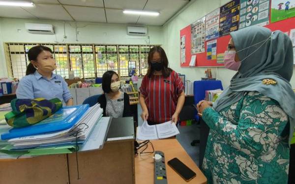 Guru Besar Sekolah Kebangsaan Pendidikan Khas Pulau Pinang (kanan) menggunakan bahasa isyarat ketika berbual dengan tiga gurunya yang menghadapi masalah pendengaran.