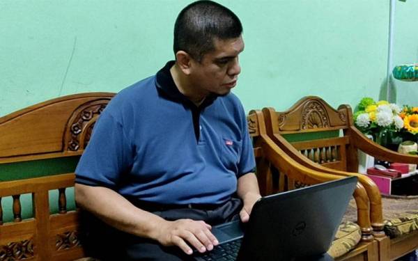 Zakaria menggunakan komputer riba yang dilengkapi sistem arahan suara (voice command) untuk mengajar pelajarnya.