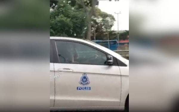 Tangkap layar video tular berdurasi 14 saat memaparkan seorang anggota polis menggunakan alat komunikasi ketika memandu di Lebuhraya Persekutuan menghala Petaling Jaya pada Ahad.