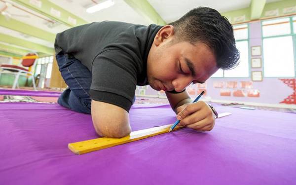 Abdullah membuat ukuran kain yang dibelinya sendiri untuk dijadikan langsir bilik darjahnya ketika ditemui di SK Tok Uban di sini baru-baru ini. - Foto Bernama