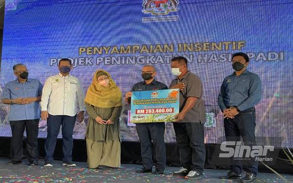 Ronald (tiga dari kanan) menyampaikan Insentif Pengurusan Pemuliharaan dan Peningkatan Kesuburan Tanah kepada salah seorang penerima.