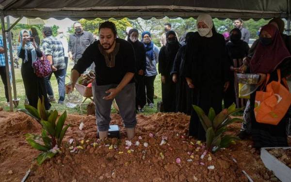 Wan Hameerudin Wan Zawawi, anak kepada Ahli akademik dan aktivis sosial allahyarham Dr Wan Zawawi Wan Ibrahim, 75, menyiram air mawar di pusara ayahnya di Tanah Perkuburan Islam Bukit Kiara pada Rabu. - Foto Bernama 