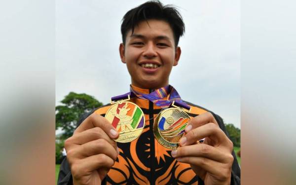 Pemain golf lelaki negara, Ervin Chang bersama pingat emas yang dimenanginya dalam acara individu dan berpasukan pada Sukan SEA ke-31 di Heron Lake Golf Course, Hanoi. - Foto Bernama