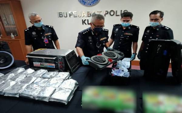 Imran (dua dari kiri) menunjukkan dadah yang disorok dalam pembesar suara ketika sidang akhbar di Balai Polis KLIA pada Khamis.