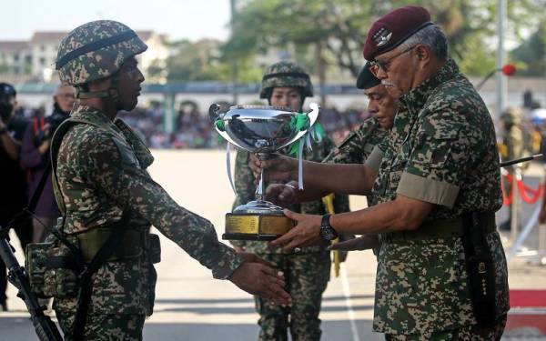 Zamrose (kanan) menyampaikan piala kepada perajurit muda Keseluruhan Terbaik, Mohamad Nor Farhan Mahzal pada acara Perbarisan Tamat Perajurit Muda Lelaki Siri 194/21 dan Wanita Siri 47/21 di PUSASDA pada Sabtu. - Foto Bernama