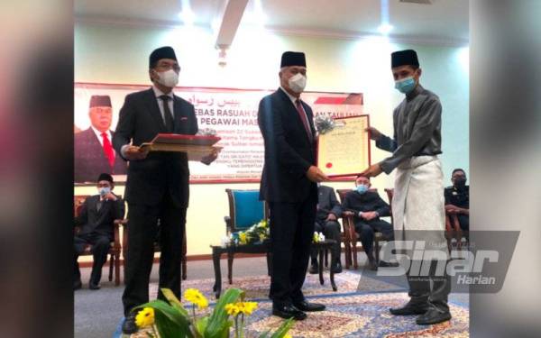 Tengku Tan Sri Mohamad Rizam (tengah) menyampaikan tauliah kepada Imam Muda Masjid Mukim Gual Tinggi, Rantau Panjang, Abdul Karim Makhtar.