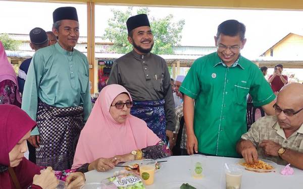 Nik Muhammad Zawawi (berdiri, tengah) bermesra dengan tetamu yang hadir pada Majlis Sambutan Hari Raya Aidilfitri LKIM Terengganu di sini pada Isnin.